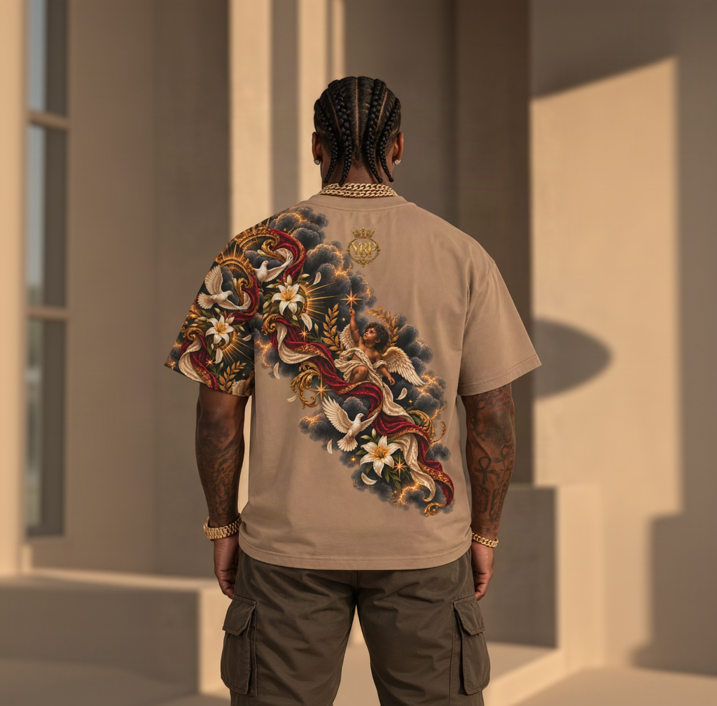 A man viewed from behind wearing a beige t-shirt with a large, detailed graphic print on the back. The print features a classical cherub, white lilies, dark clouds, and red drapery.