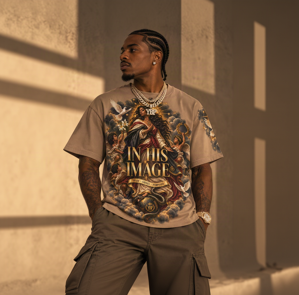 A man wearing a beige graphic t-shirt with a detailed religious illustration and the text 'IN HIS IMAGE'.